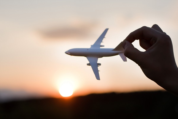 Person playing with toy plane with sun setting in background