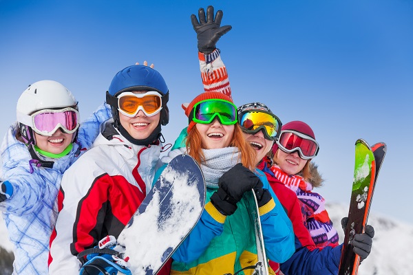 Happy group of friends with snowboards and skis