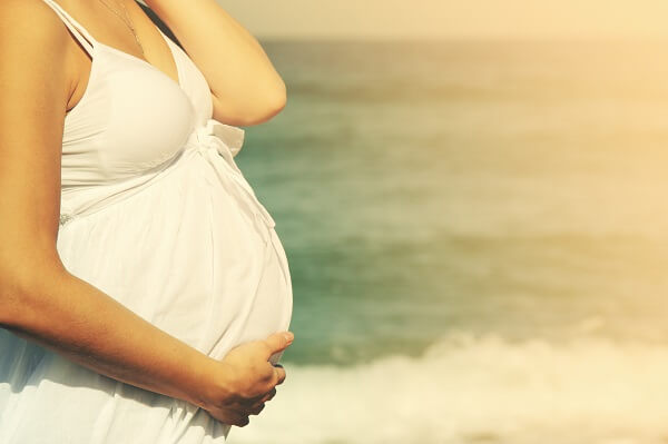 beautiful pregnant woman standing on the beach