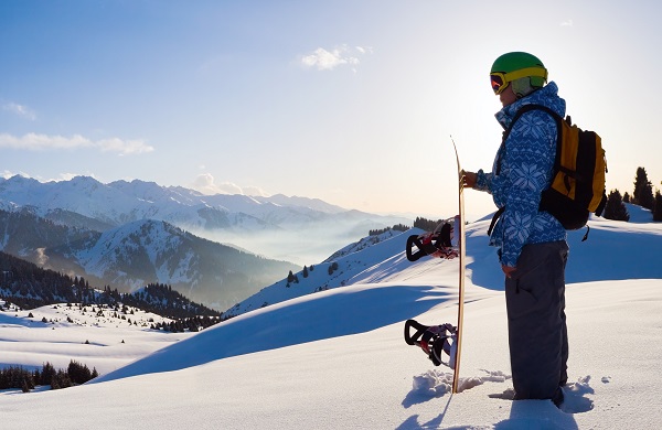 Snowboarder stood on slope looing at the view