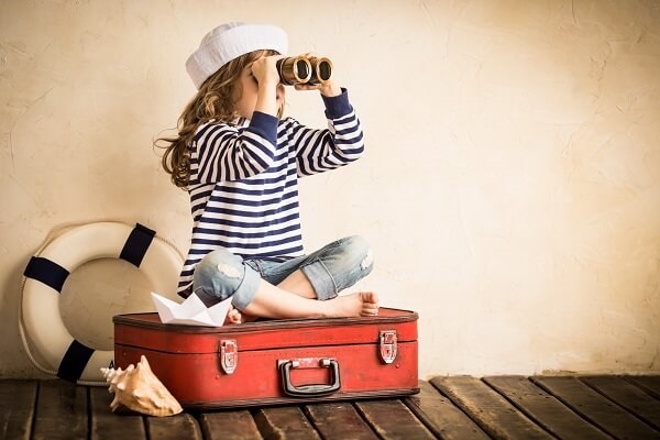 Family travel packing, kid sat on suitcase