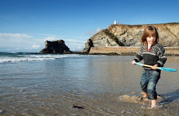 little girl with a spade, digging sand on a beach in Cornwall