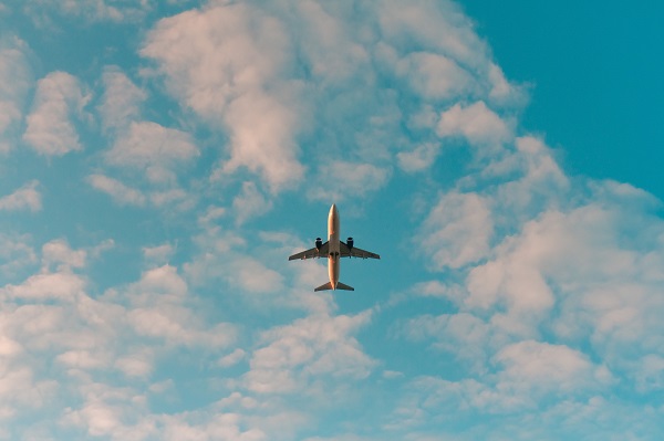 aeroplane flying overhead through slightly cloudy blue sky