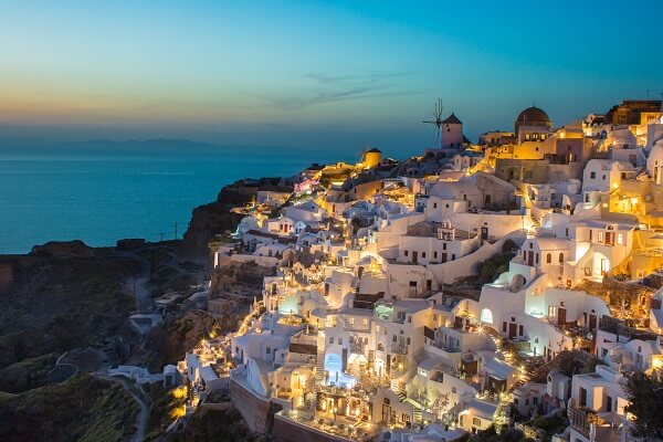 lit up white apartments on a hillside in greece by the sea